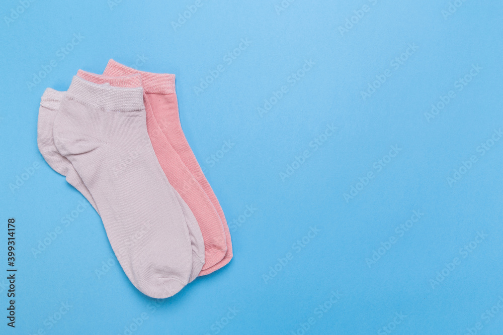 two pairs of multicolored new socks stacked on a blue background. top view. two pairs of multicolored new socks stacked on a blue background. top view.