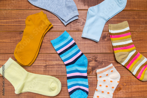 multicolored new socks in different sizes stacked on a wooden background. clothes for women