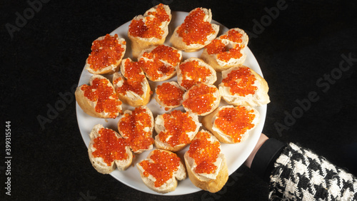 Sandwiches with red caviar and butter on baguette on the dark background. Cuisine concept.