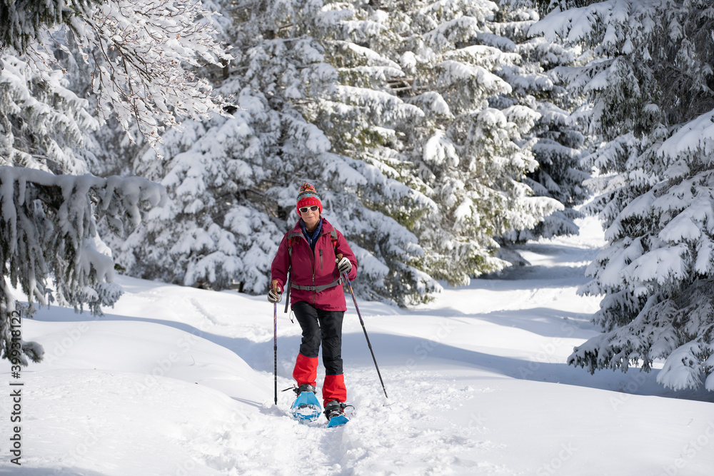 nice and active senior woman snowshoeing in deep powder snow in the Allgau alps, Bavaria, Germany