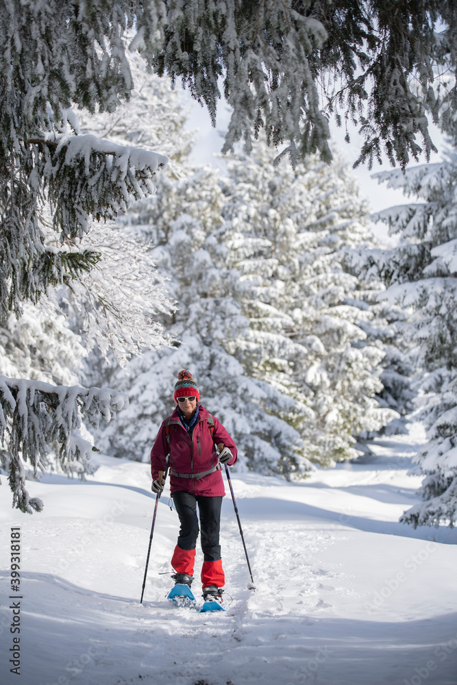 nice and active senior woman snowshoeing in deep powder snow in the Allgau alps, Bavaria, Germany