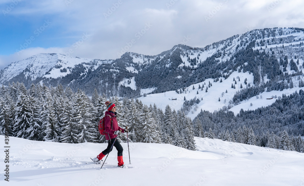 nice and active senior woman snowshoeing in deep powder snow in the Allgau alps, Bavaria, Germany