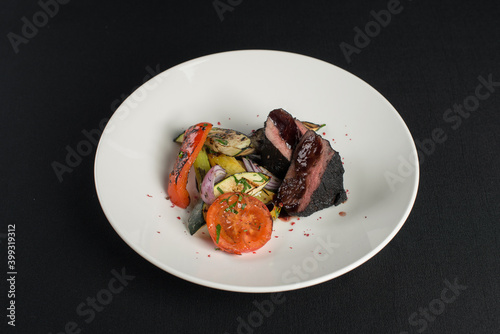 veal tenderloin in ashes with grilled vegetables on a white plate photo