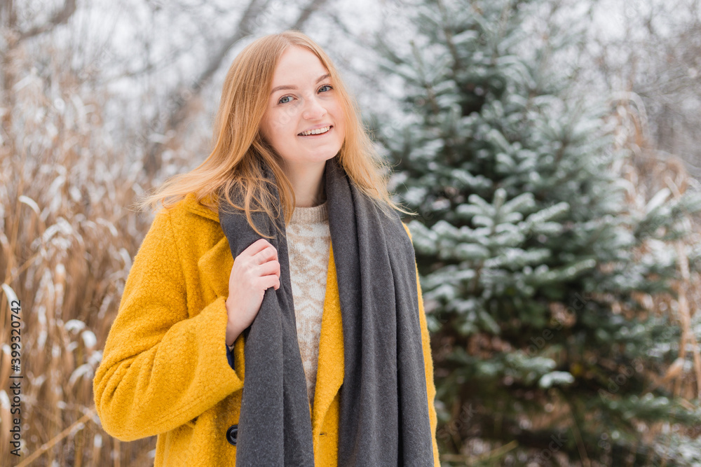 Happy young woman wearing a coat and scarf smiling over nature background, trendy color of year 2021 - illuminatiing yellow and ultimate gray, winter time Happy young woman wearing a coat and scarf smiling over nature background, trendy color of year 2021 - illuminatiing yellow and ultimate gray, winter time