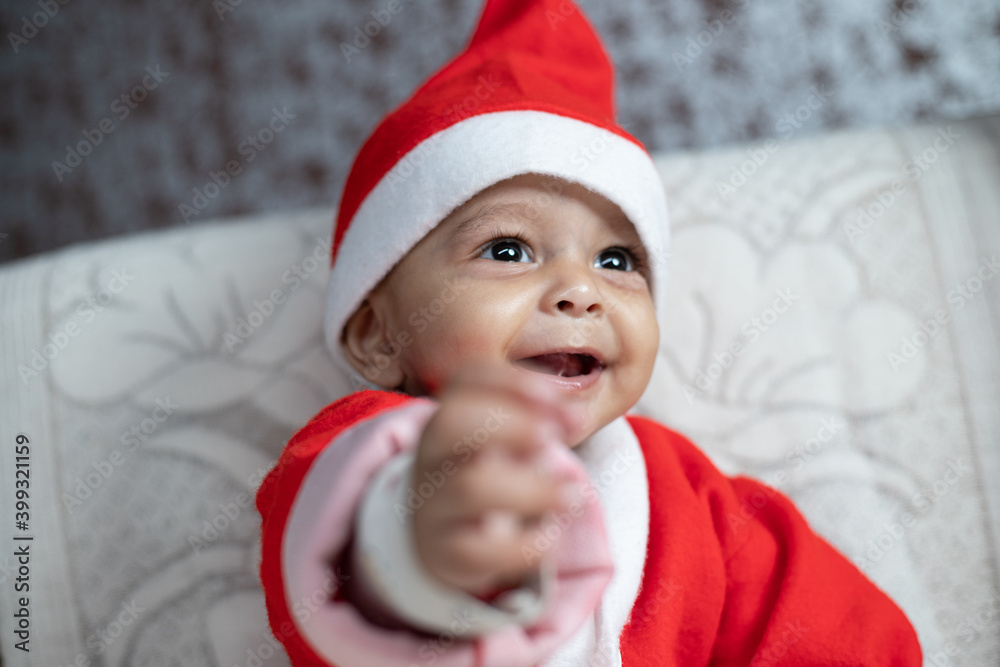 Portrait of Baby smiling in Santa costume with tree in background Portrait of Baby smiling in Santa costume with tree in background