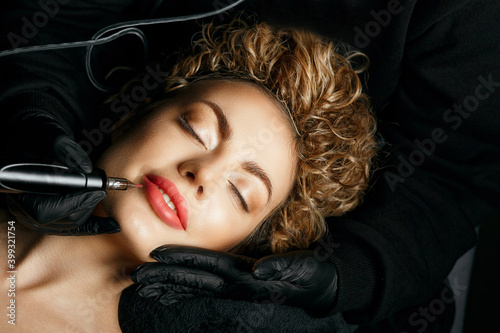 Master making lip permanent procedure to a blonde woman photo