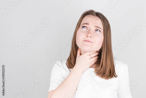 Throat pain. Ill woman with sore throat suffering from pain, touching neck with hand.
