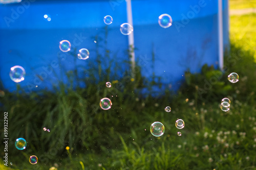 Rainbow bubbles floating in the garden park. Summer playful background.