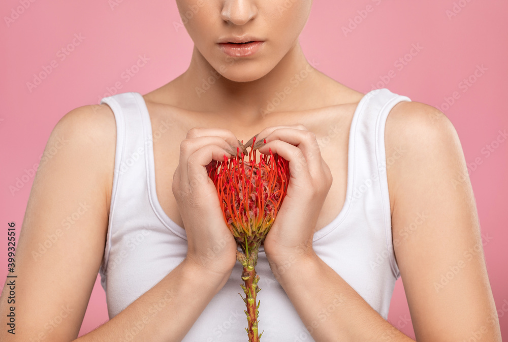 Young women holding a flower near her chest. Personal care, cosmetology and makeup concept. Young women holding a flower near her chest. Personal care, cosmetology and makeup concept.