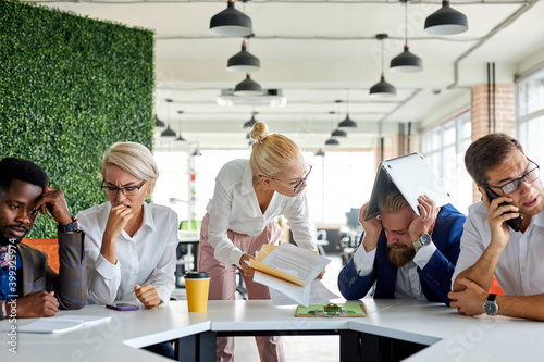 Fotografie team of sad frustrated employees receiving rebuke by shouting female executive,