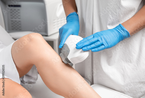 Elos epilation hair removal procedure on a woman’s body. Beautician doing laser rejuvenation on the lower leg in a beauty salon. Removing unwanted body hair. Hardware ipl cosmetology