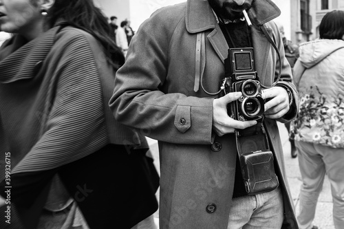 Hipster guy with the vintage camera photographing people in the city - Photojournalist with a famous retro camera taking photo in the crowd during street demonstration - Street photography style