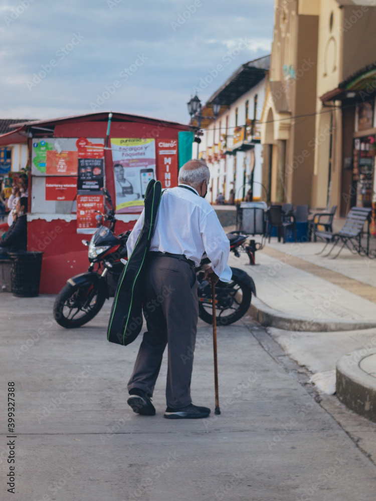Obraz premium señor caminado con una guitarra por la calle