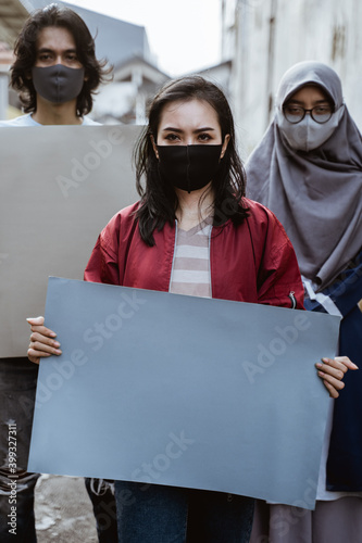 Portrait students holding blank paper conducting demonstrations by following health protocols photo