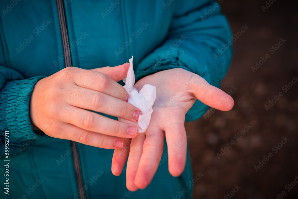 Girl wipes her hands with a napkin outside in frost