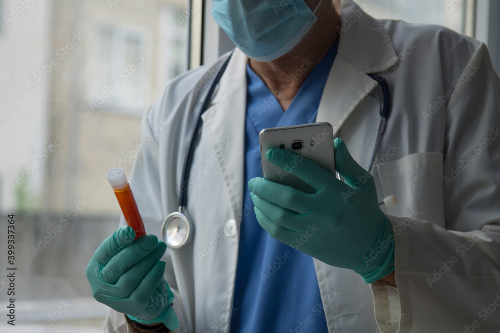 doctor holding a test tube with blood for 2019-nCoV analysis and mobile phone in the other hand. New Chinese coronavirus blood test concept doctor holding a test tube with blood for 2019-nCoV analysis and mobile phone in the other hand. New Chinese coronavirus blood test concept