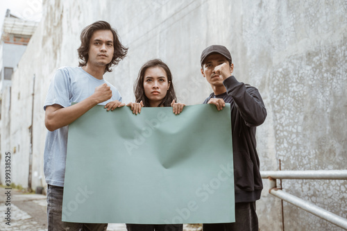 Portrait students holding blank paper who are burning with enthusiasm doing a demonstration together photo