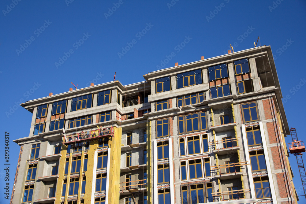Contemporary urban architecture. Facade of a multi-storey building under construction. Brick building under construction.