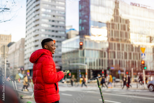 Young man using smart phone outdoors at urban setting 