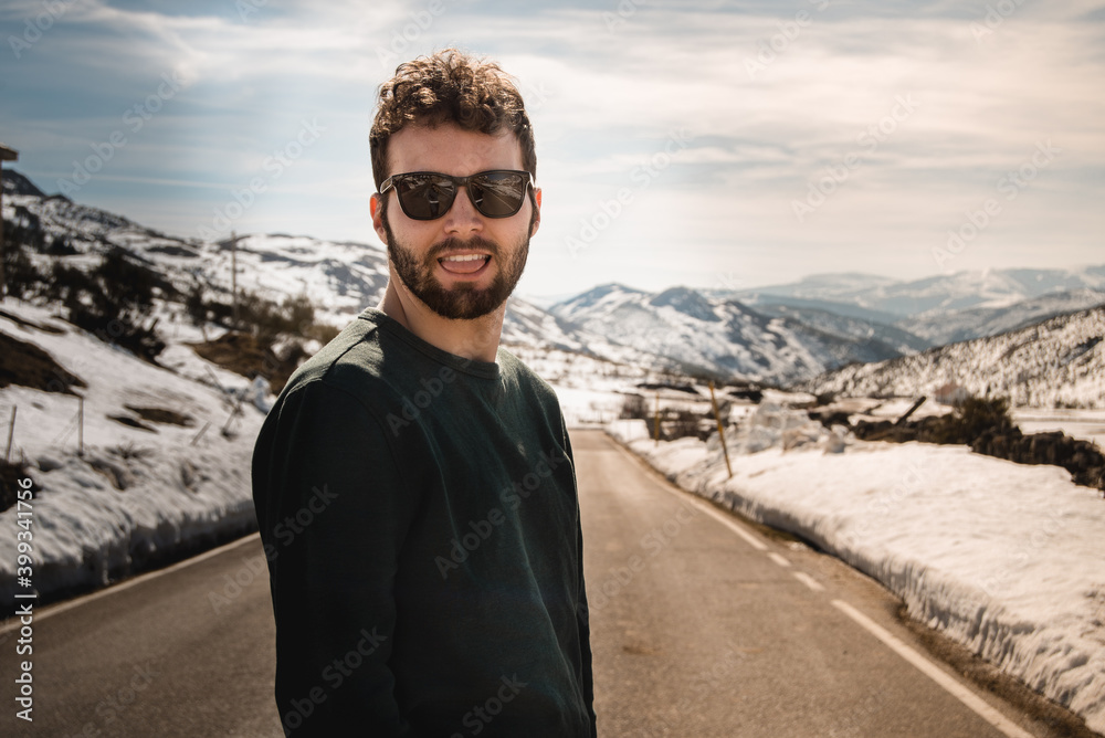 Hombre sonriente feliz en gafas de sol posando en la nieve al aire libre