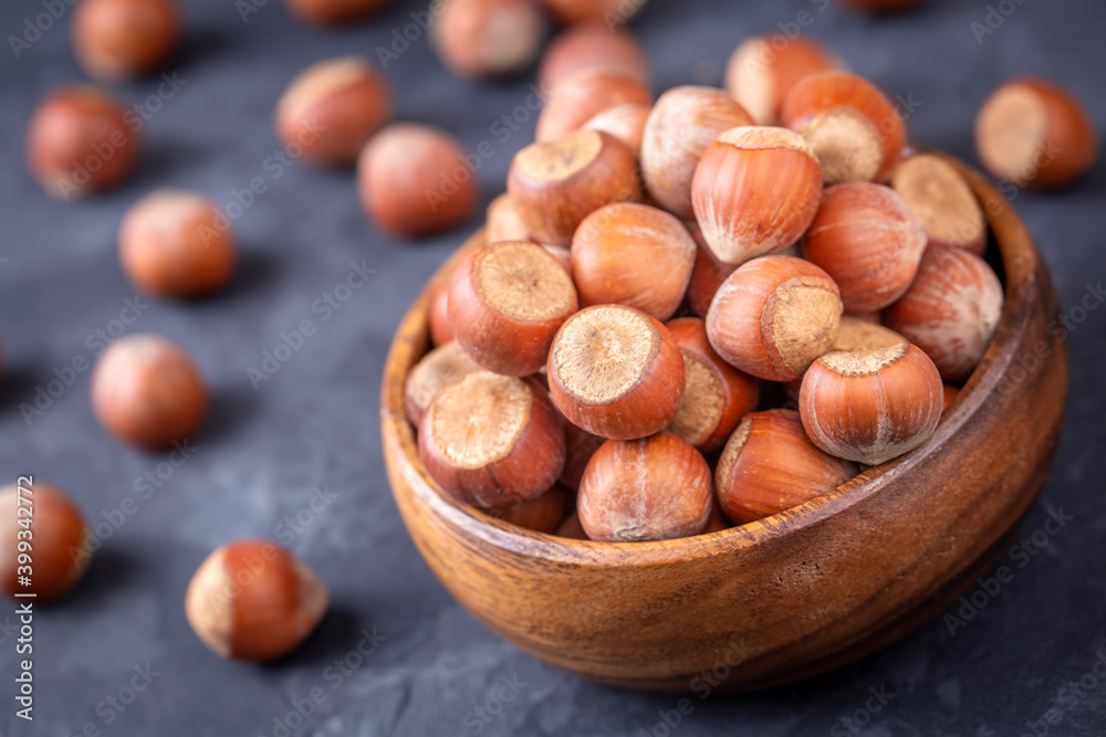 Hazelnut in wooden bowl on black background. Organic hazelnut. Hazelnut in wooden bowl on black background. Organic hazelnut.
