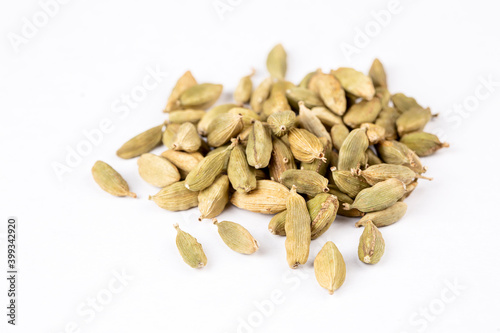 Closeup top view of dried green Elettaria cardamomum fruits with seeds, cardamom spice scattered on white background