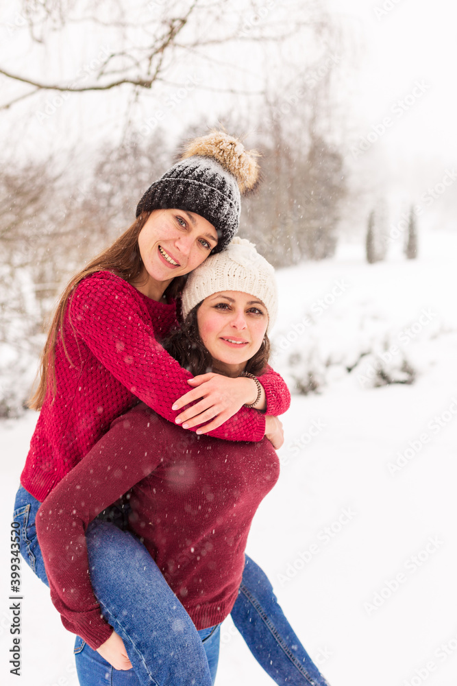 Obraz premium TWO GIRLS IN RED SWEATERS IN THE WINTER FOREST. THE SISTERS WALK IN THE SNOW IN THE PARK