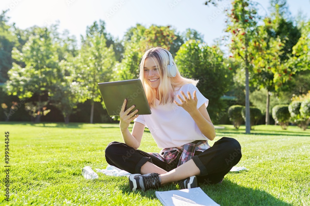 Teenager girl in headphones looking in digital tablet and talking on video communication Teenager girl in headphones looking in digital tablet and talking on video communication