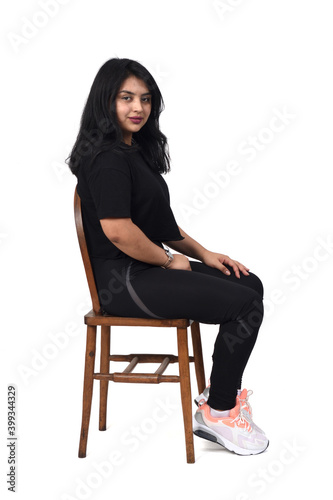 side view of a latin woman sitting on a chair white background,