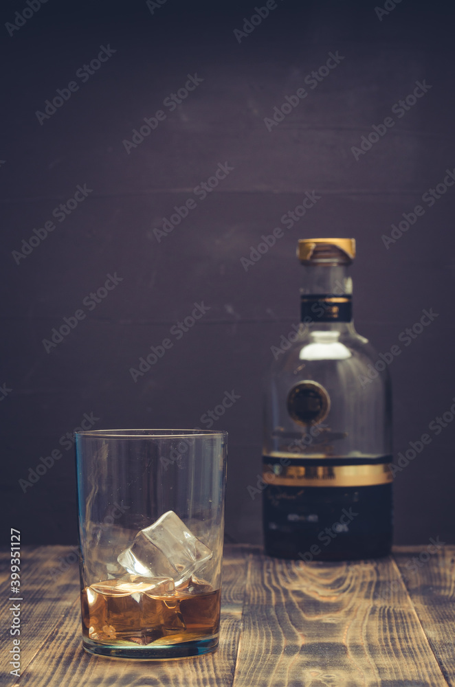 Whiskey cocktail with ice on a wooden surface. Selective focus. Alcoholic beverage on the dark background.