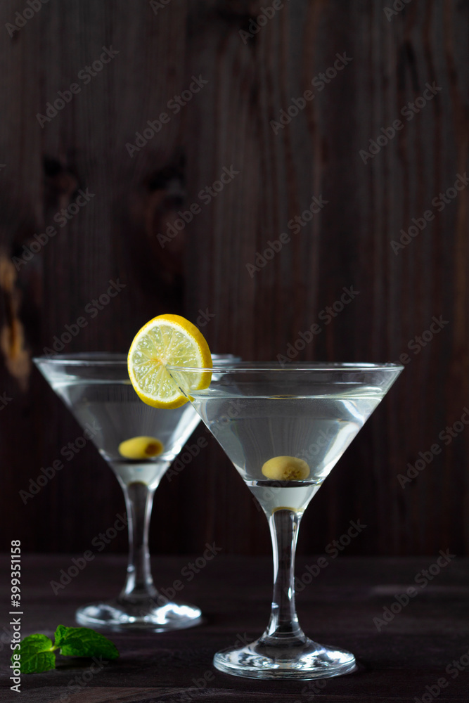 Two Martini glasses with cocktail and olives on black background. Cocktail Margarita with lime and green mint on the wooden table. copy space. alcohol drinks. vertical.