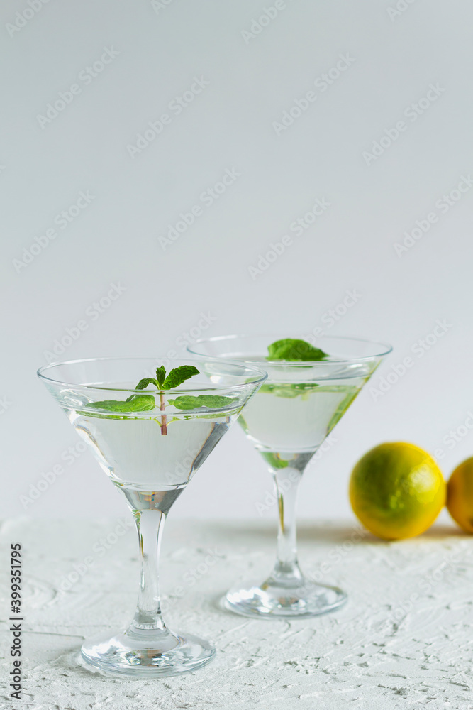 alcohol drinks. Two martini glasses with cocktail on white background. Cocktail Margarita with lime and green mint on the table. copy space. vertical