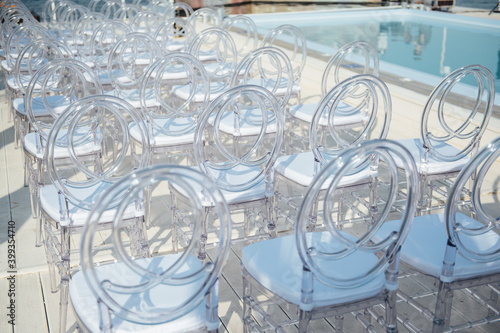 Glass chairs stand in a row in a beautiful wedding outing ceremony