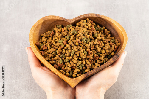Pet food in heart shaped bowl in woman hands, pet love concept