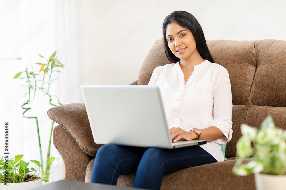 Pretty young woman working in laptop on sofa at home Pretty young woman working in laptop on sofa at home