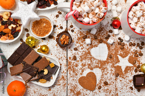 sweet food top view background for merry christmas or new year holiday decoration - chocolate candies, tangerines, cookies, marshmallow and cocoa latte on white wood