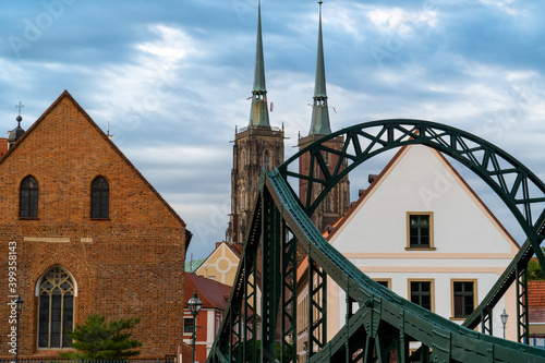 A beautiful old-style green metal bridge, behind it a tower from the cathedral.