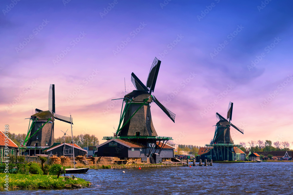 Netherlands rural landscape. Traditional Dutch windmills with canal in Zaanse Schans village during sunset.