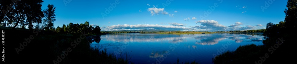 Panoramic view of a calm lake on a sunny summer day Panoramic view of a calm lake on a sunny summer day