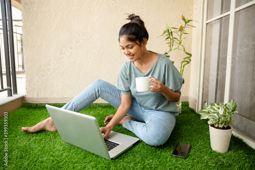Photography Pretty Young woman working on laptop with coffee cup at balcony artificial grass
