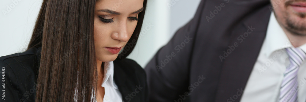 Attractive brunette lady texting message on smartphone while working with colleague in office