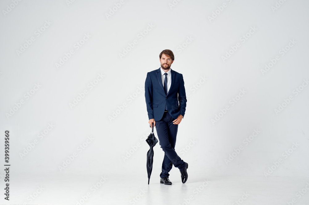 business man with an umbrella and in a classic suit in full growth on a light background business man with an umbrella and in a classic suit in full growth on a light background