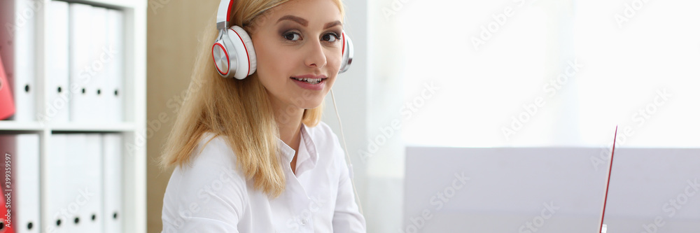 Attractive blonde lady sitting at the table and writing on notebook in modern office Attractive blonde lady sitting at the table and writing on notebook in modern office