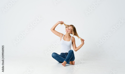 women legs crossed sitting on the floor indoors in jeans and t-shirt 