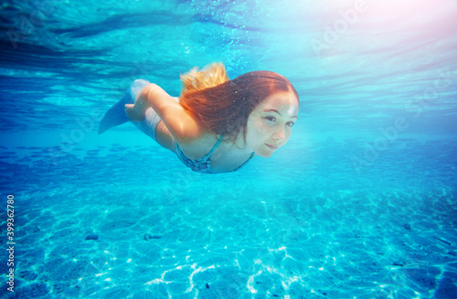 Portrait of a girl mermaid with tail and long hair swim under water in the ocean