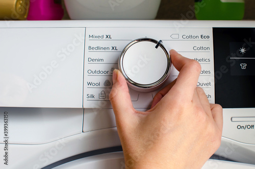 Foto Hand turning the knob of the tumble dryer to adjust the temperature