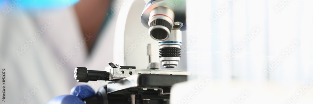 Close up of male researcher in sterile gloves looking at biological samples under microscope Close up of male researcher in sterile gloves looking at biological samples under microscope