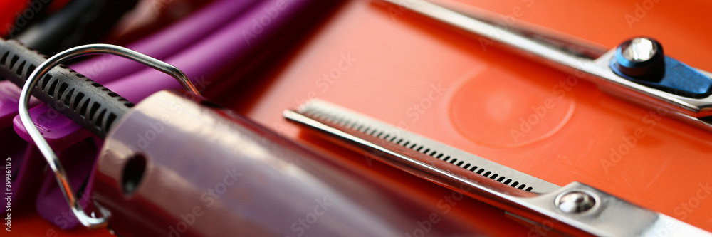 Close up of professional hairdressing scissors, hair clipper and hairgrips on red surface - obrazy, fototapety, plakaty 