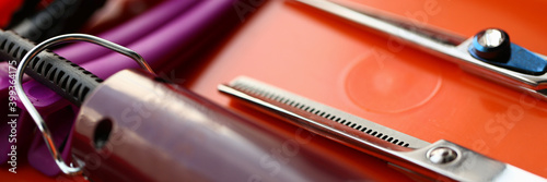 Close up of professional hairdressing scissors, hair clipper and hairgrips on red surface photo