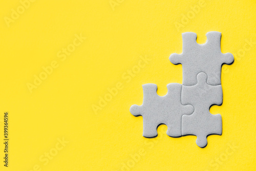 Demonstrating trendy Color of the Year 2021. Illuminating Yellow and Ultimate Gray. Duotone. Multiple grey puzzle pieces put together without one piece on yellow background